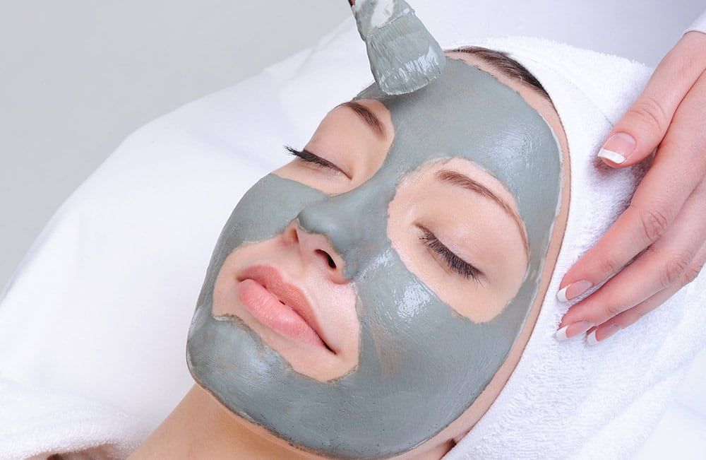 Higiene facial profunda con mascarilla purificante aplicada por esteticista profesional